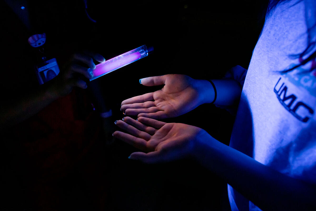 A student holding up a black light on a person's palms