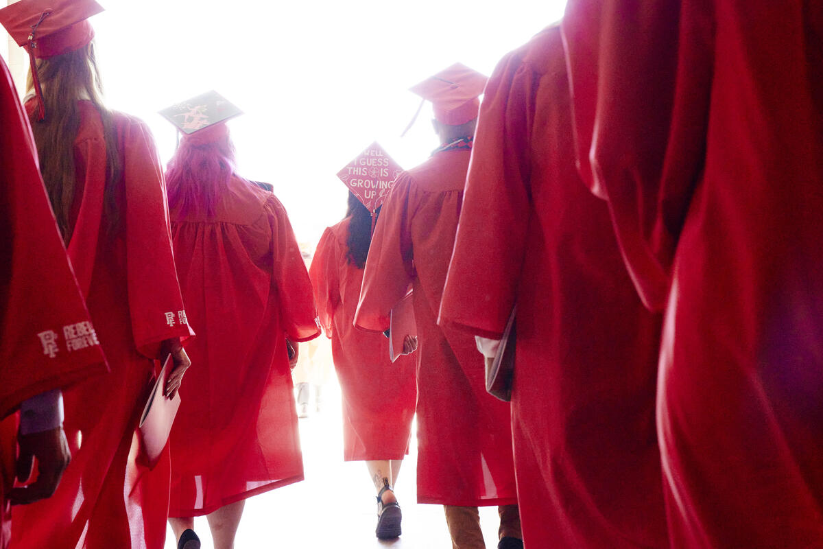 Students in red caps and gowns walking.
