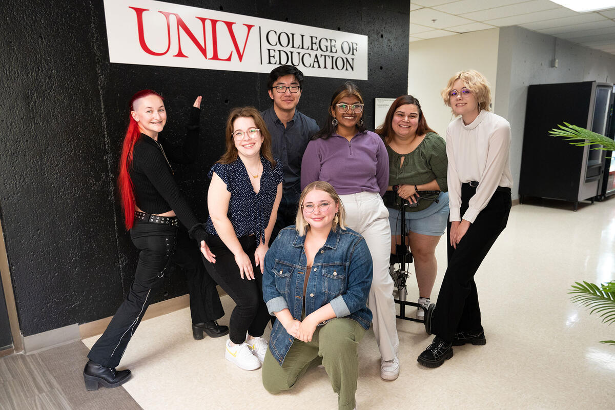 A group of people standing around the UNLV College of Education signage