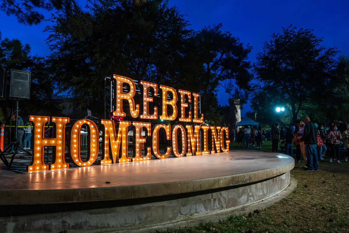 Light up letters spell "Rebel Homecoming" at dusk.