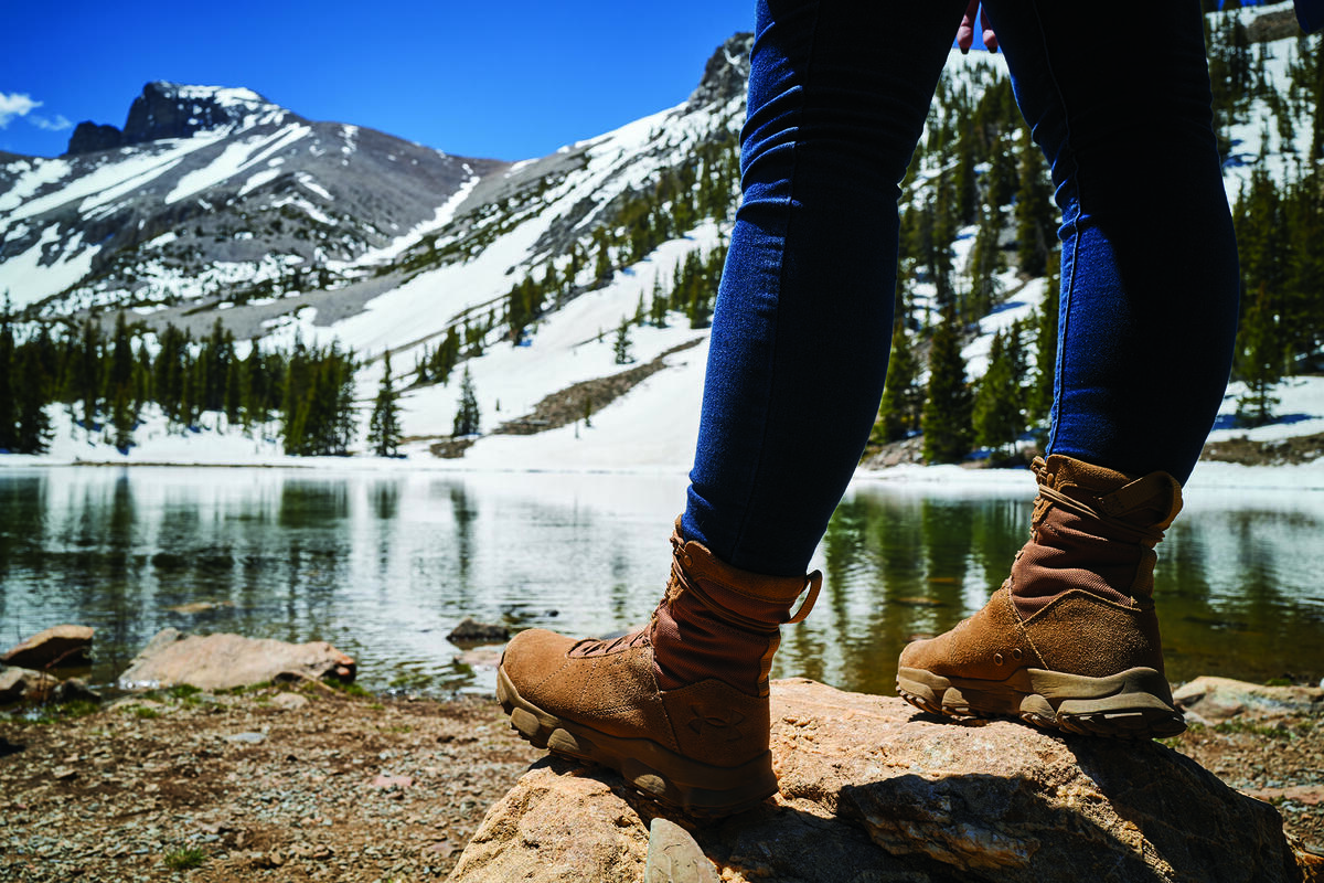 closeup of hiking boots at edge of mountain lake