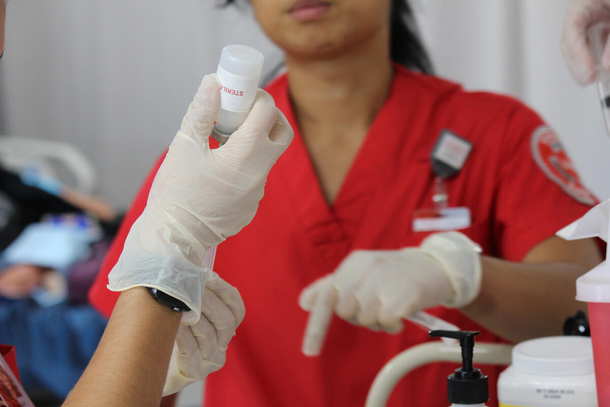 Female medical professional pointing. Vial is being held in focus