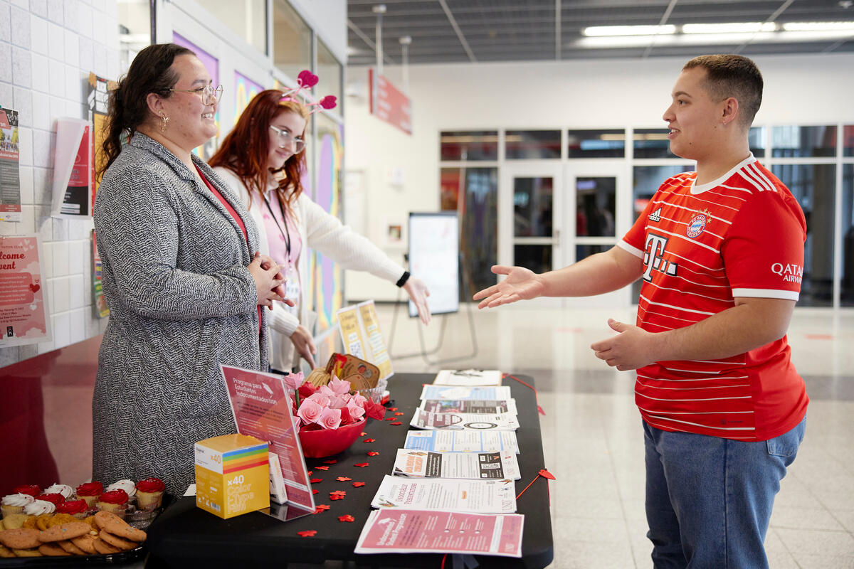 Student speaks with program representatives at a table.