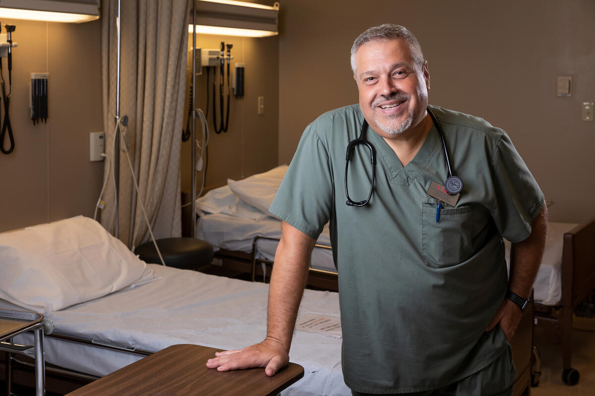 physician in scrubs leaning on hospital bed
