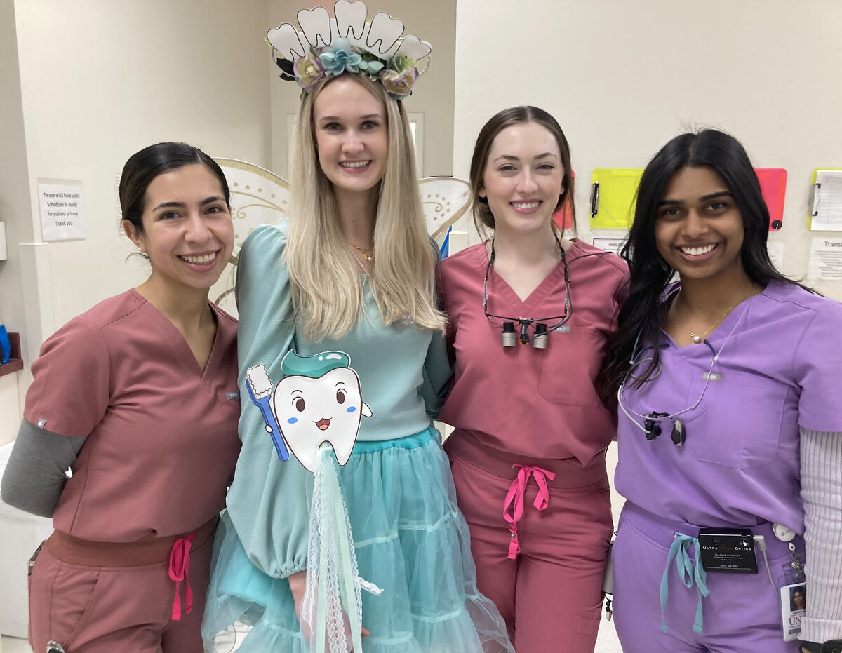 group of 3 females in scrubs and 1 dressed up as a tooth fairy