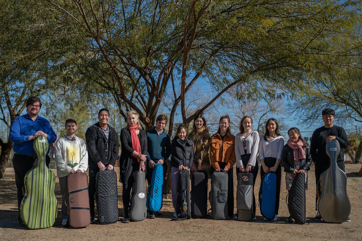 group of stringed instrument musicians standing under tree