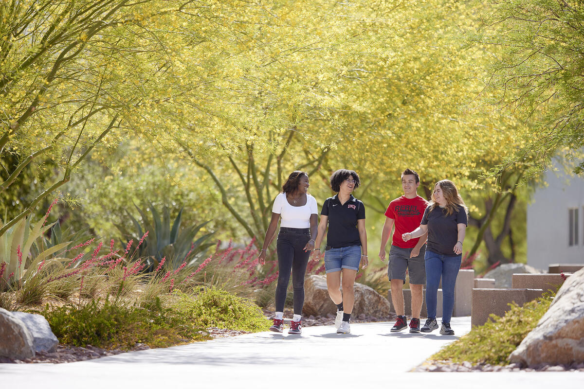 four students talking while walking outdoors