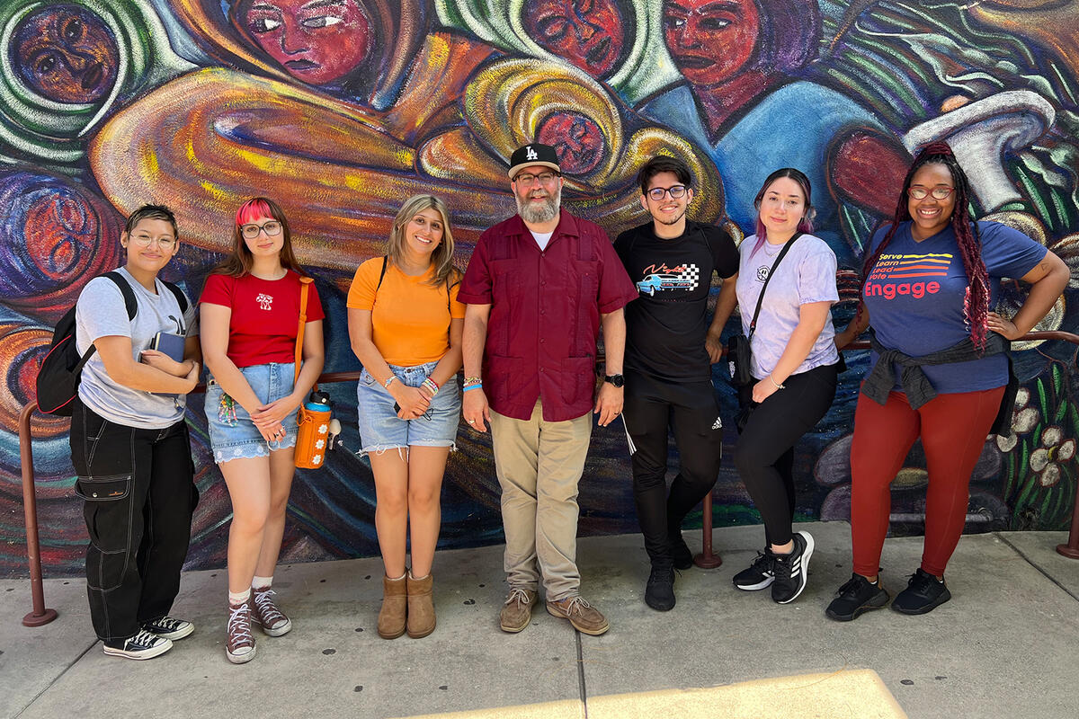 group of students and mentor in front of a mural