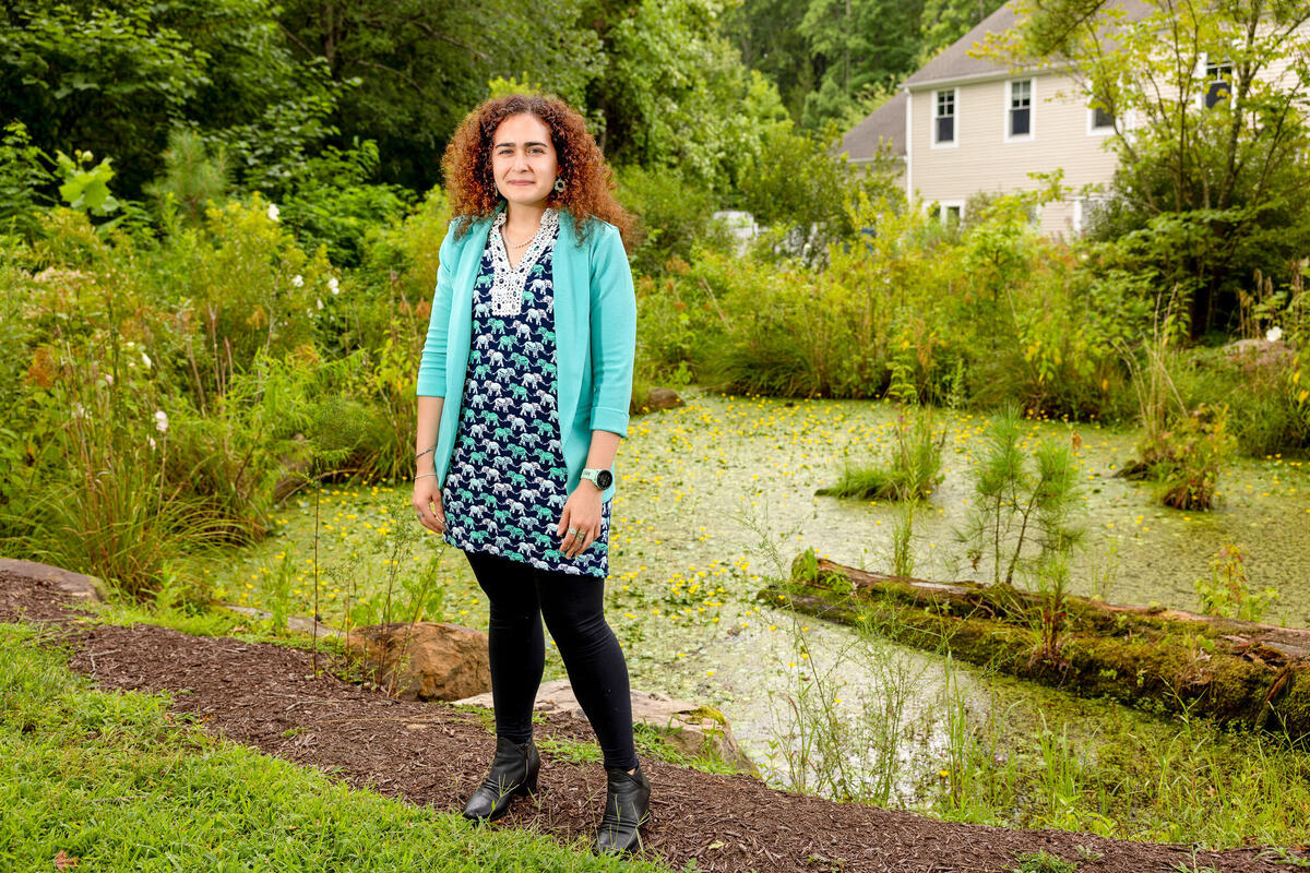 woman standing outside in front of pond and bushes