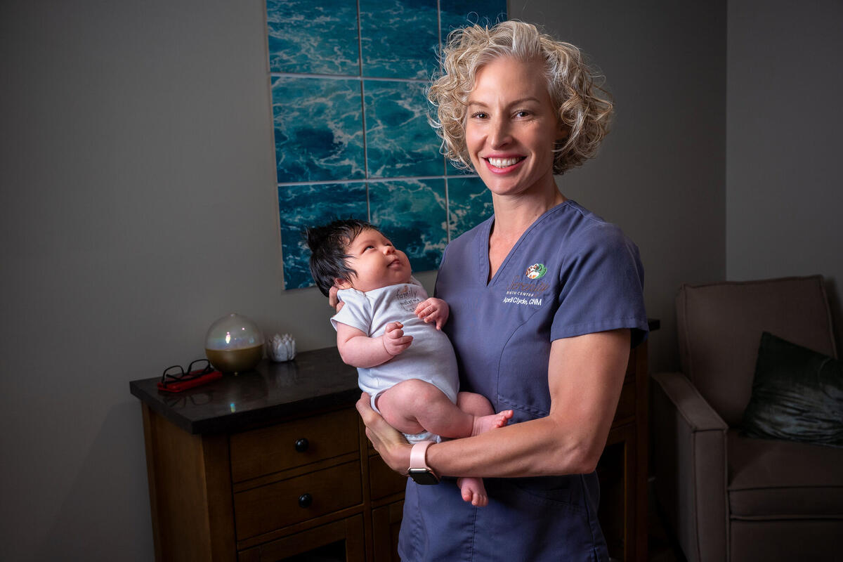 woman in blue scrubs holding a baby