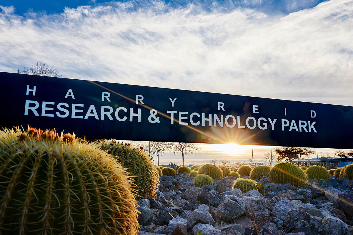 A sign that reads &quot;Harry Reid Research &amp; Technology Park&quot; with rocks and cacti surrounding it.