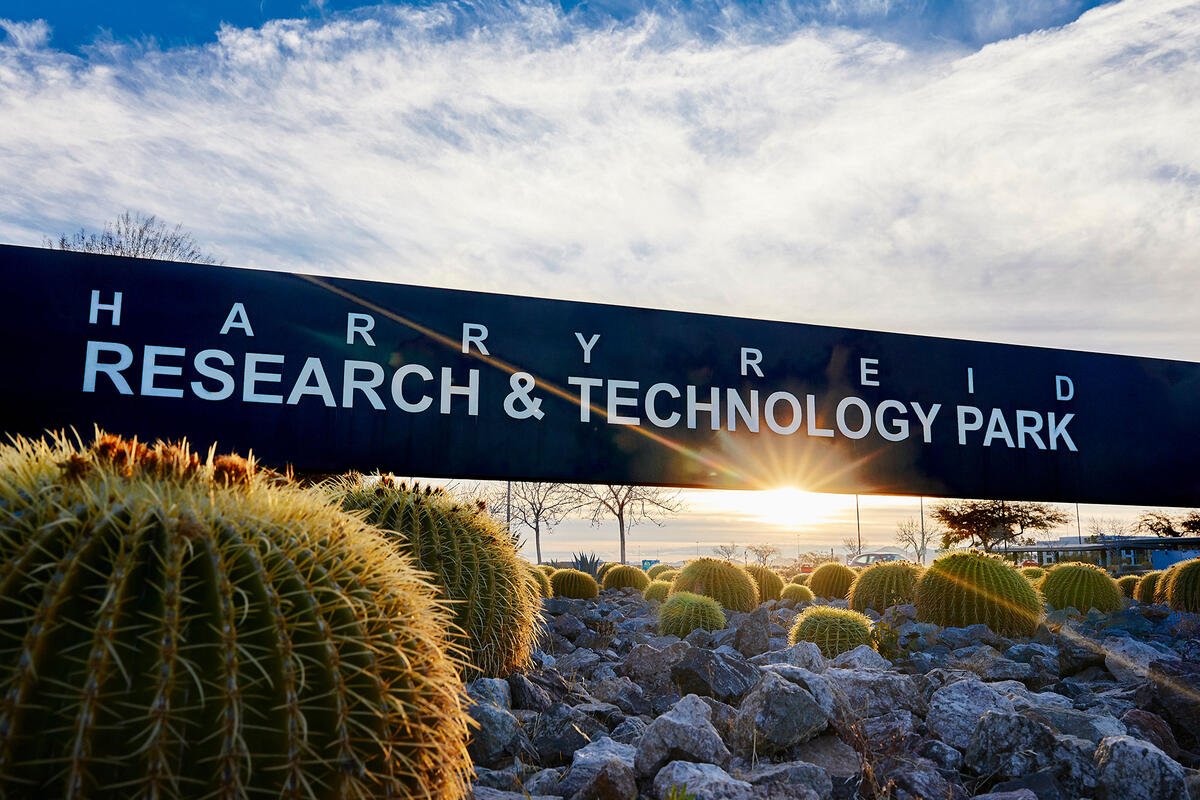 A sign that reads "Harry Reid Research & Technology Park" with rocks and cacti surrounding it.