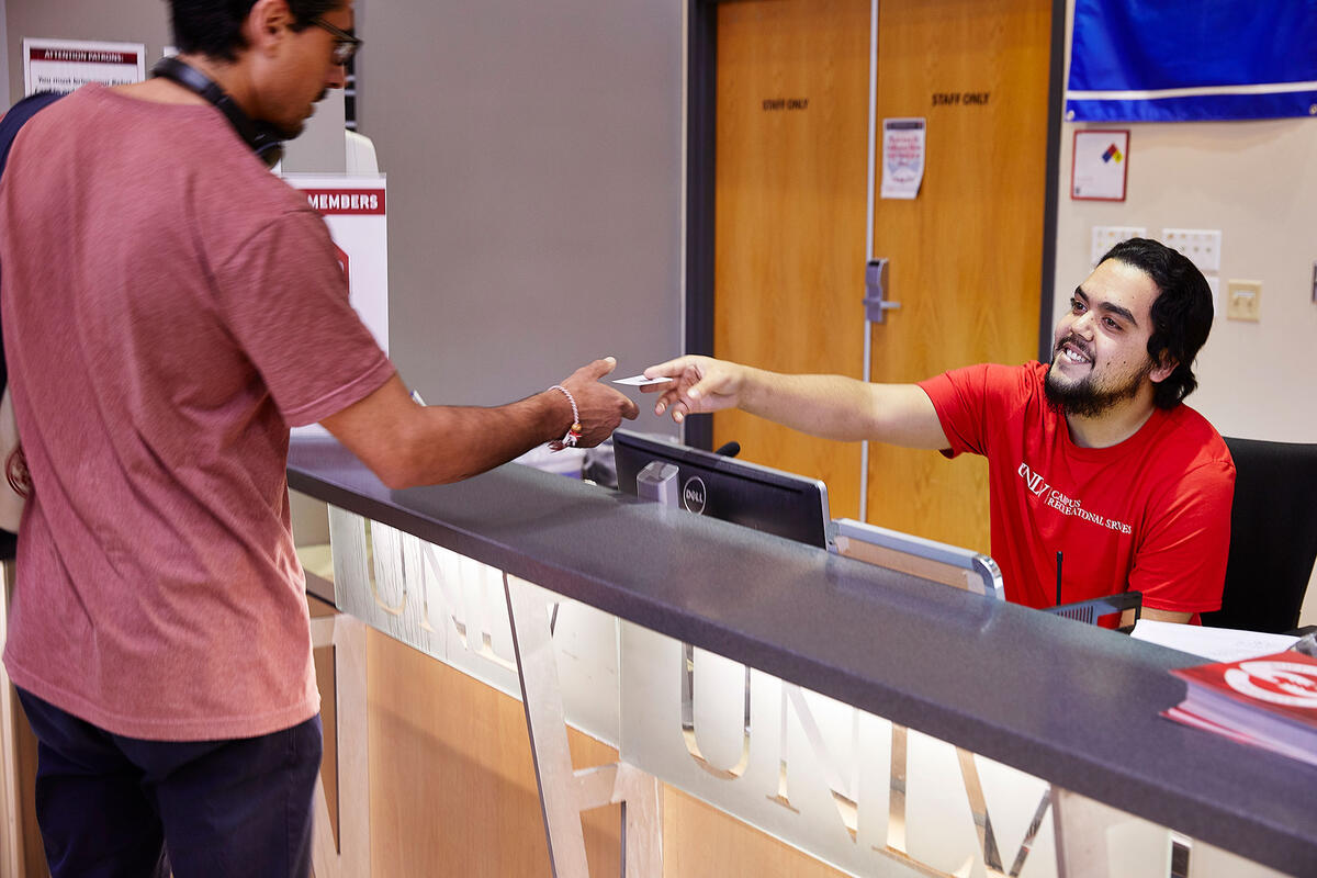 A man at a front desk handing over a card to a person