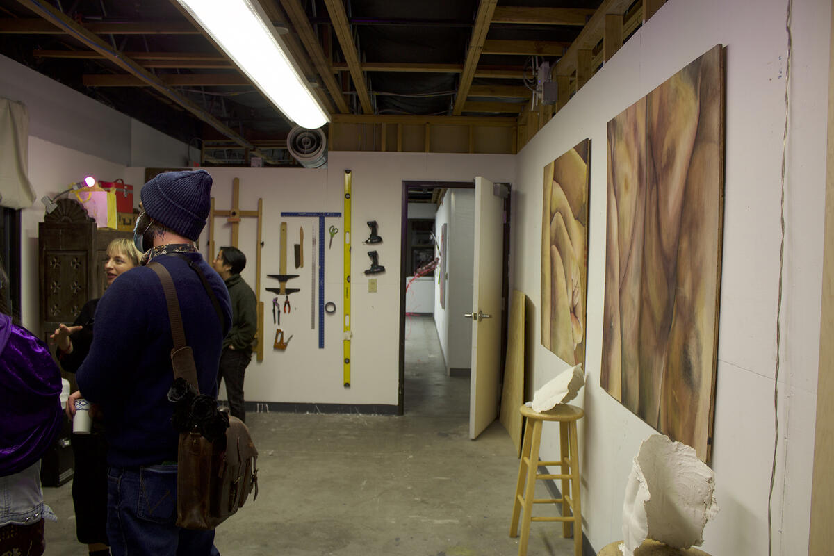 People in a studio glancing at art hanging on walls