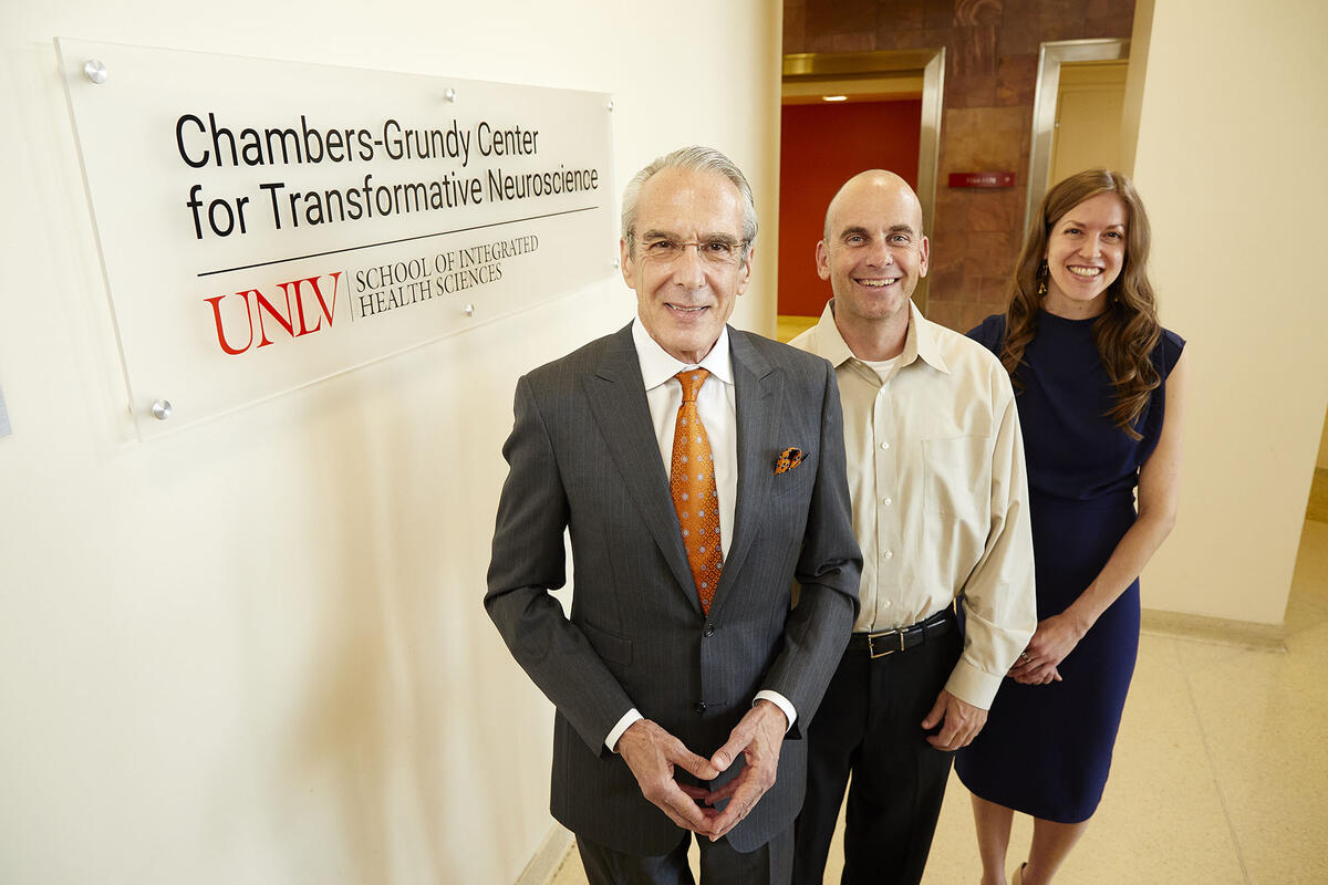 Three people standing in front of sign that says &quot;Chambers-Grundy Center for Transformative Neuroscience&quot;