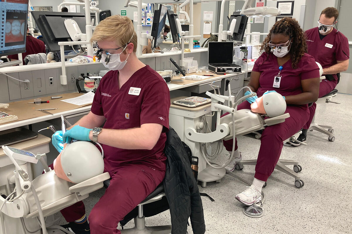 Three dental students in a simulation lab