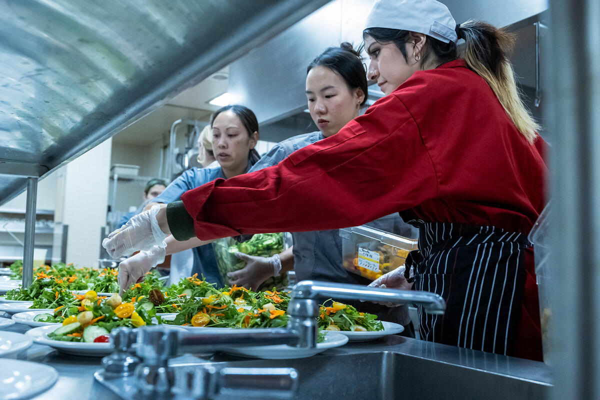 Photo of people in a kitchen garnishing plates