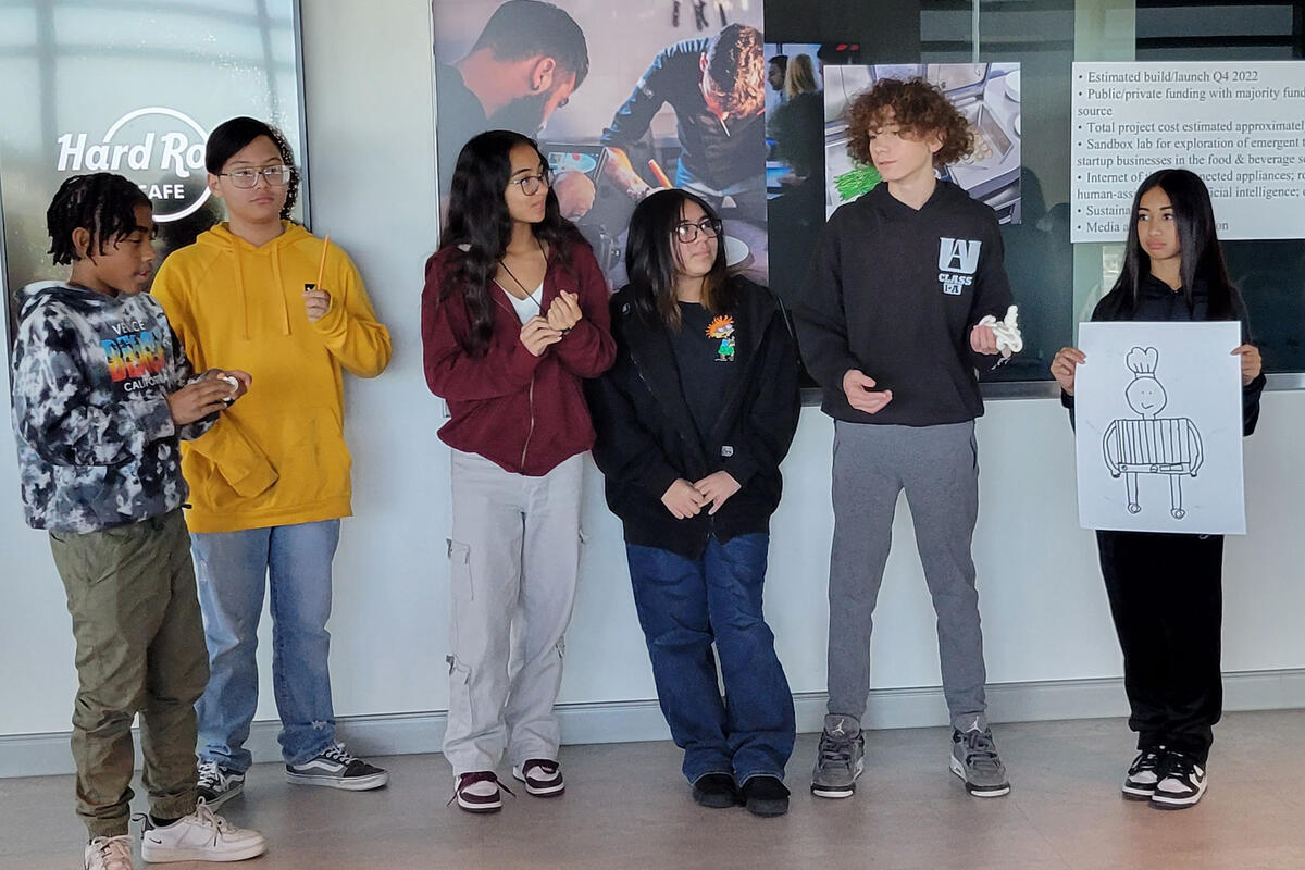 Group of student standing in a hallway, one holding a drawing of a chef