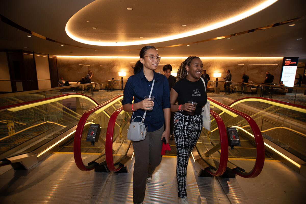 Two women walking off of escalator