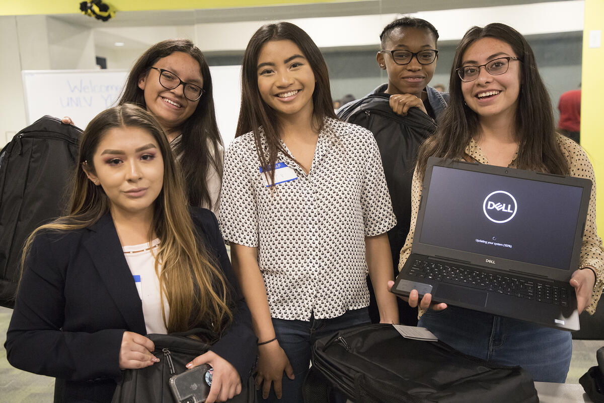 People standing around while one person holds a laptop to the camera