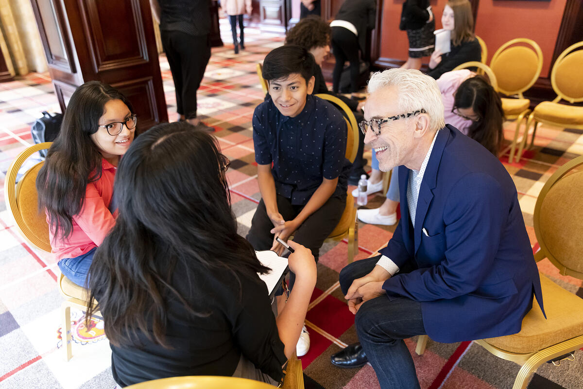 Older man talking to group of students gathered around him