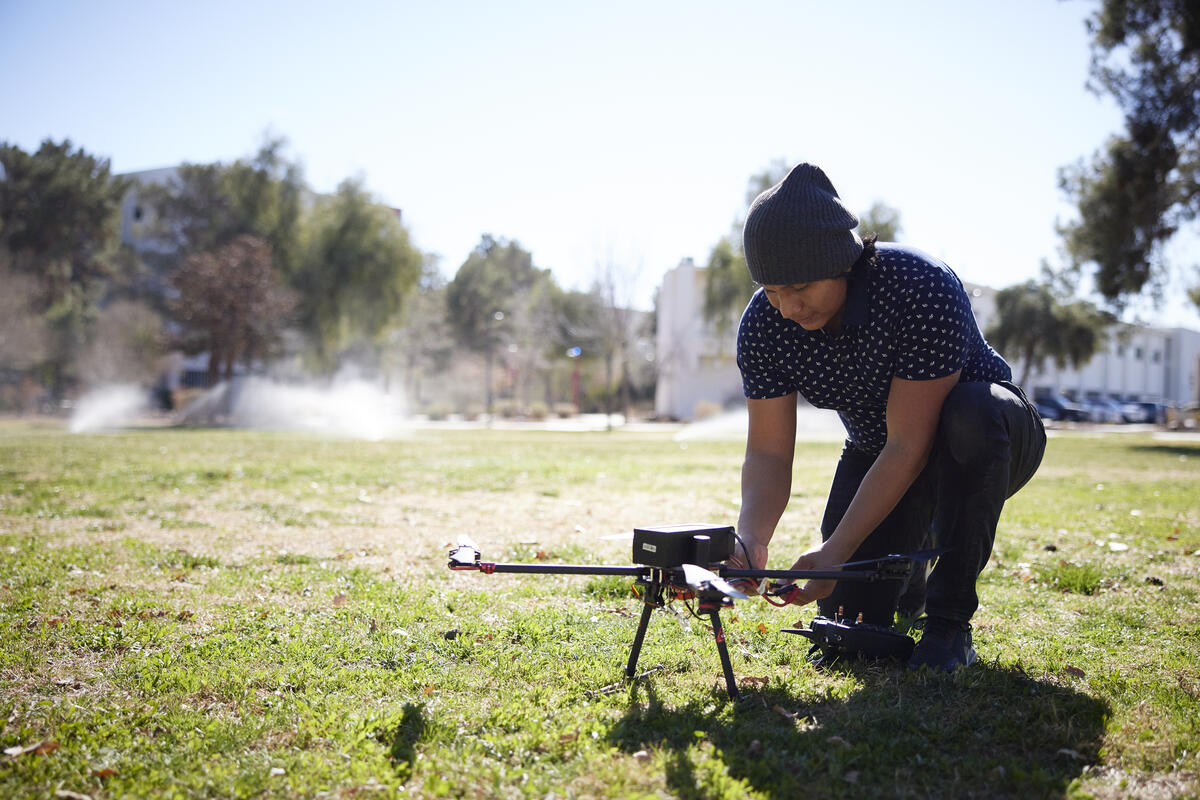 person setting up a drone on the grass