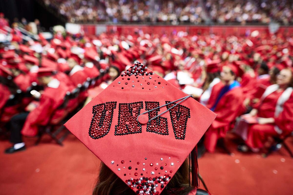 Graduation ceremony, person in foreground has &quot;UNLV&quot; written in rhinestones on their graduation hat