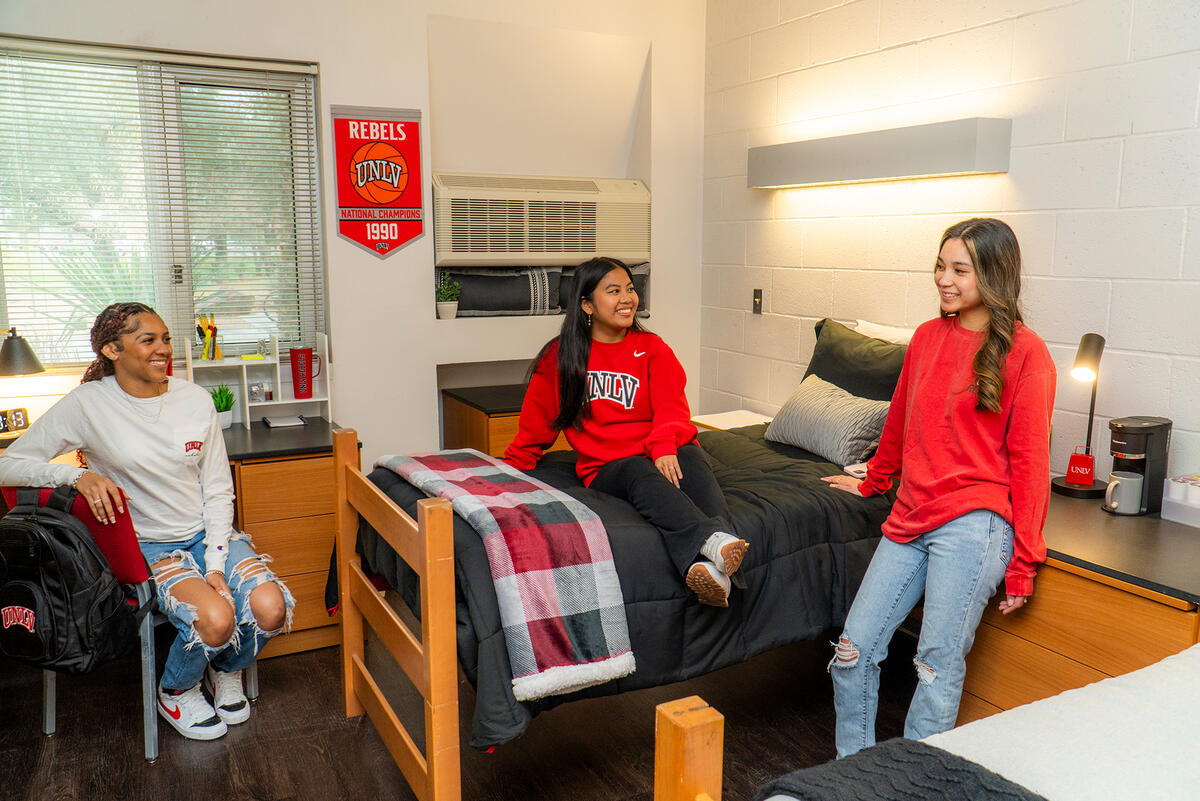 two girls sitting looking at another girl at a UNLV dorm room