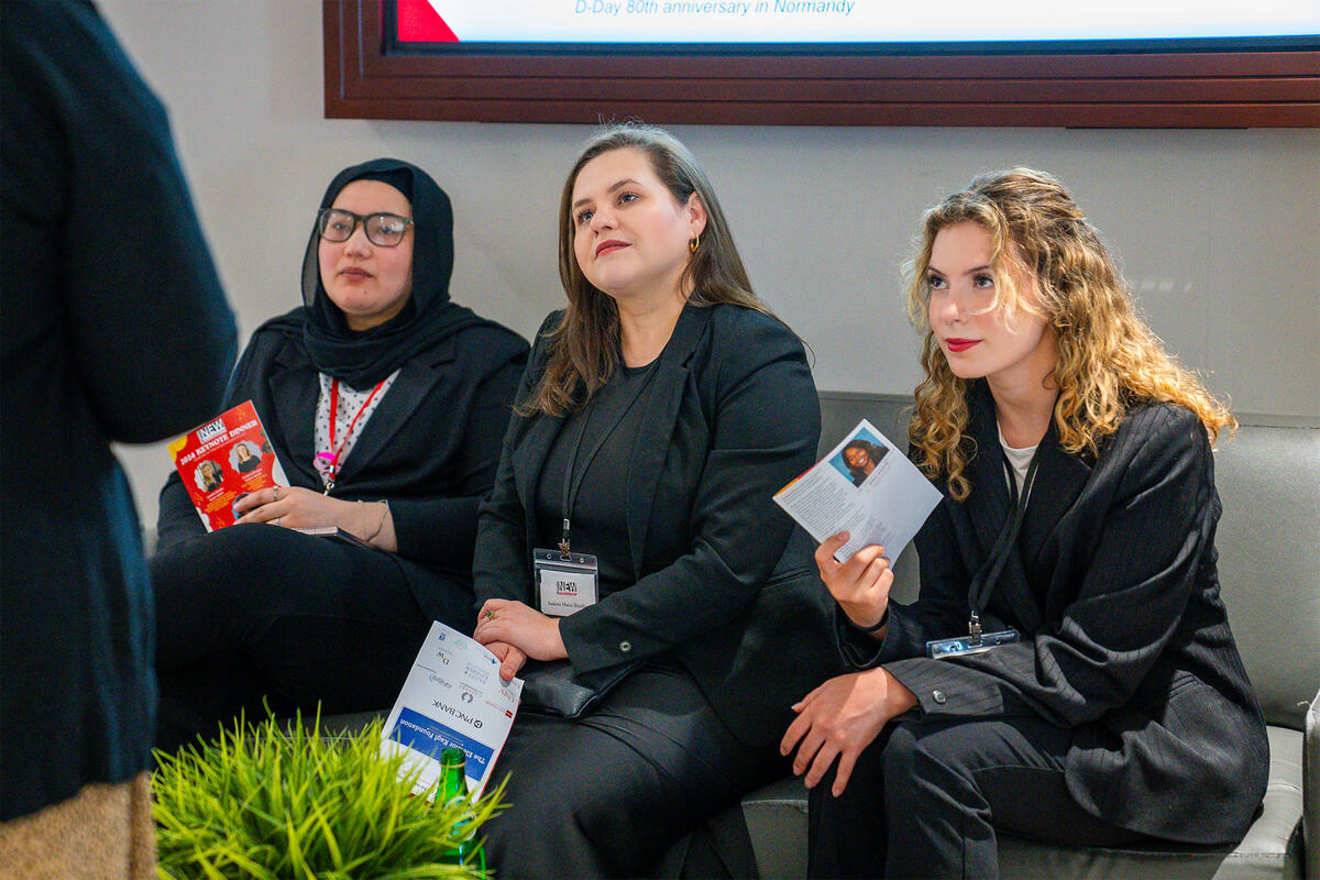 Three women sitting down on a couch while holding a pamphlet 
