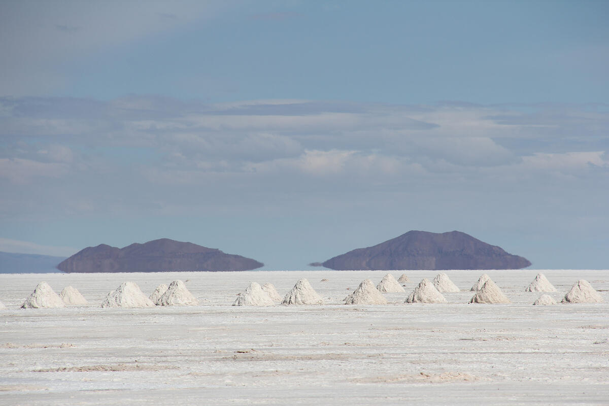 Flatlands with white sand or fine gravel, numerous piles of the sand/gravel all in a row, and two hills in the background