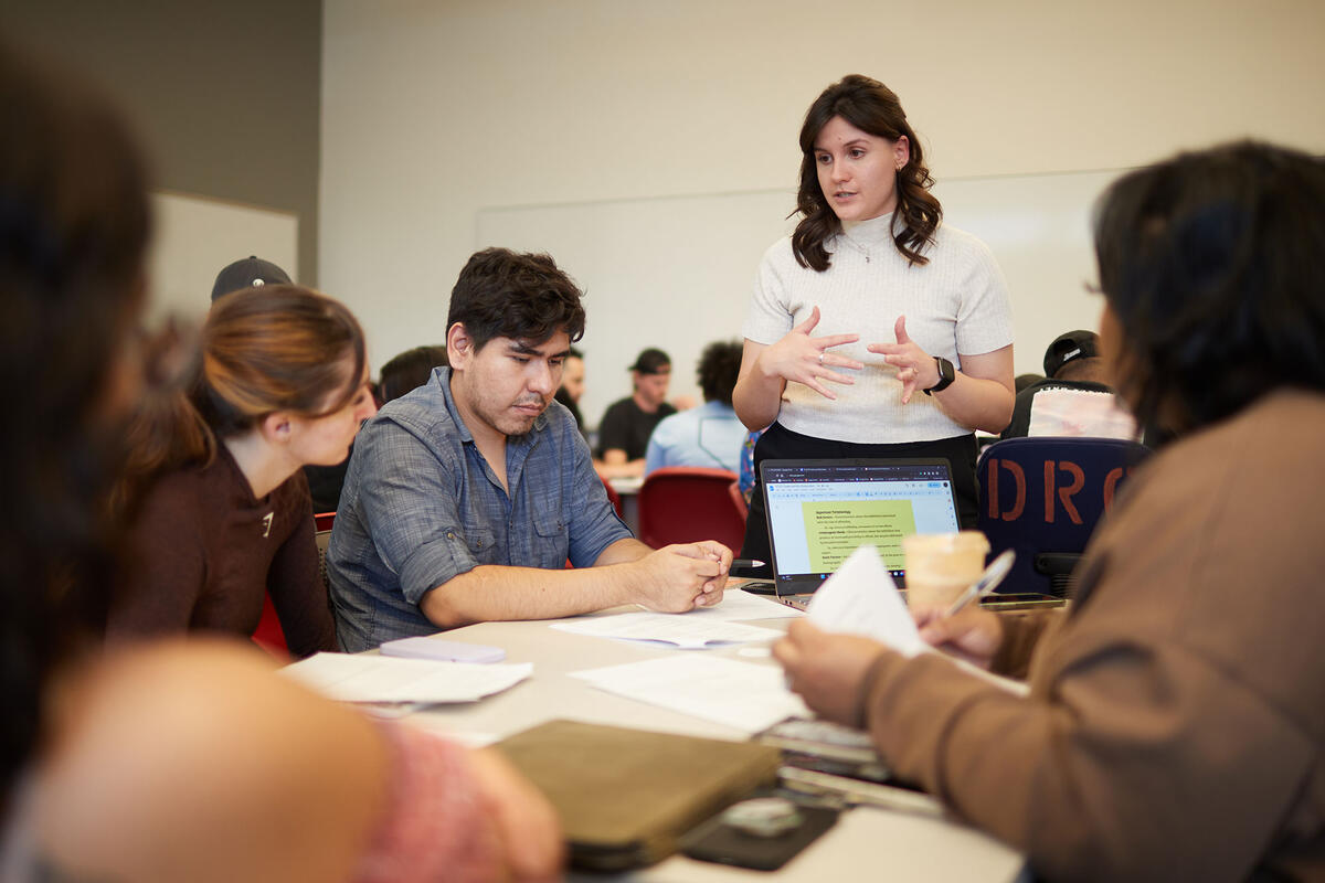 A woman speaking in front of a group of people sitting down