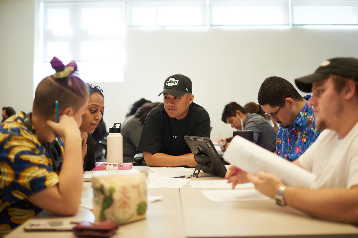 A group of people sitting down at a table taking notes