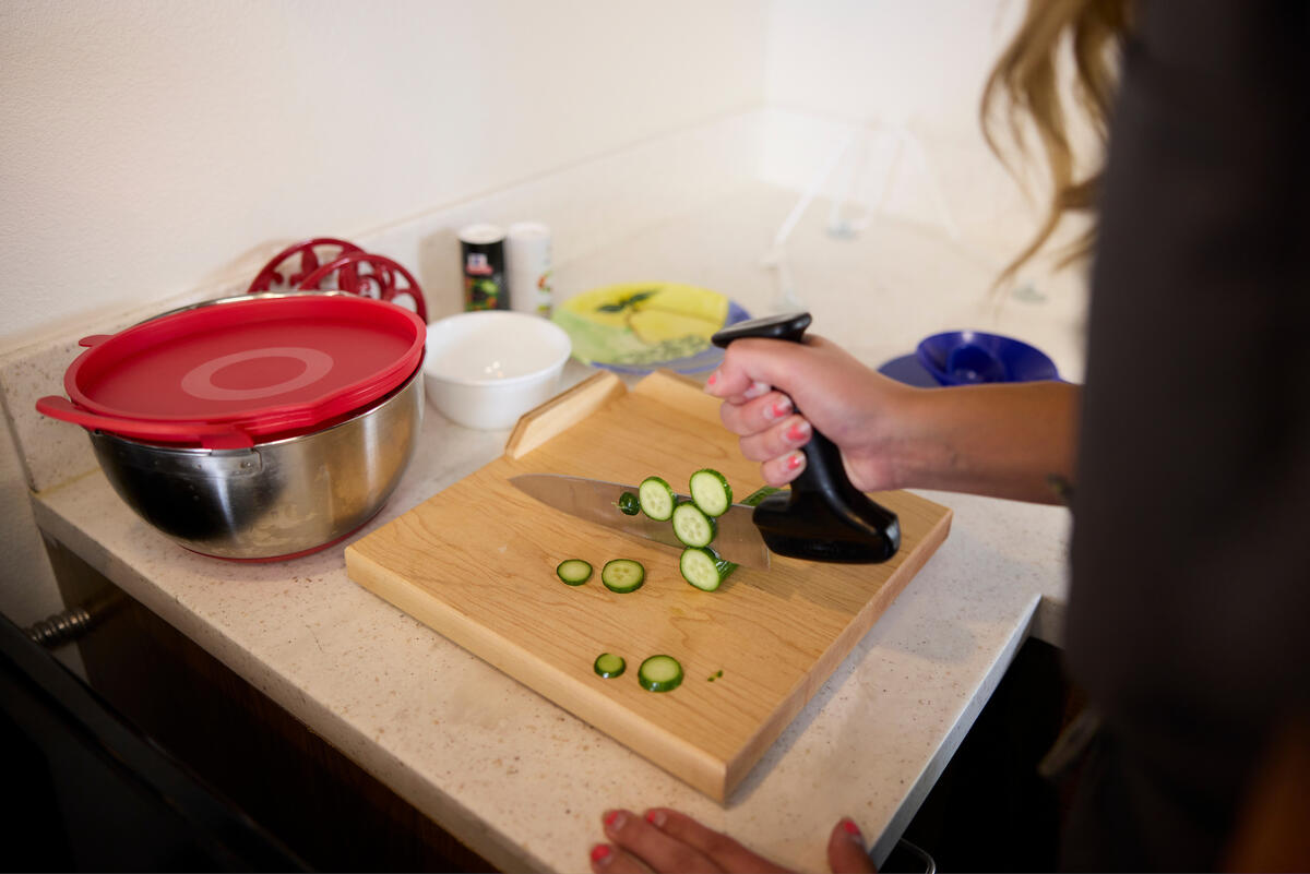 Occupational therapy student using a right angle knife to cut a cucumber