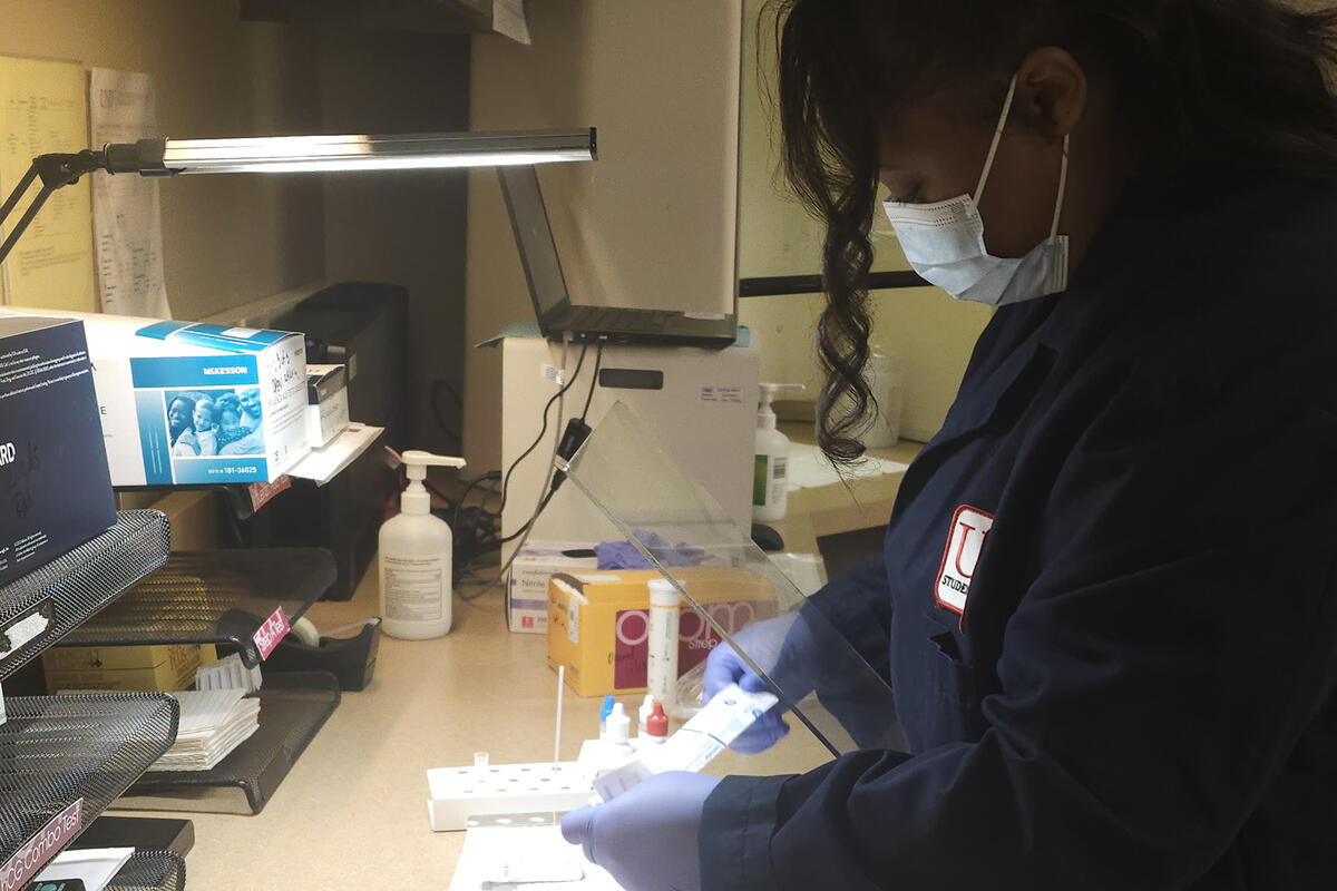 Lab worker looking at specimen under lamp light