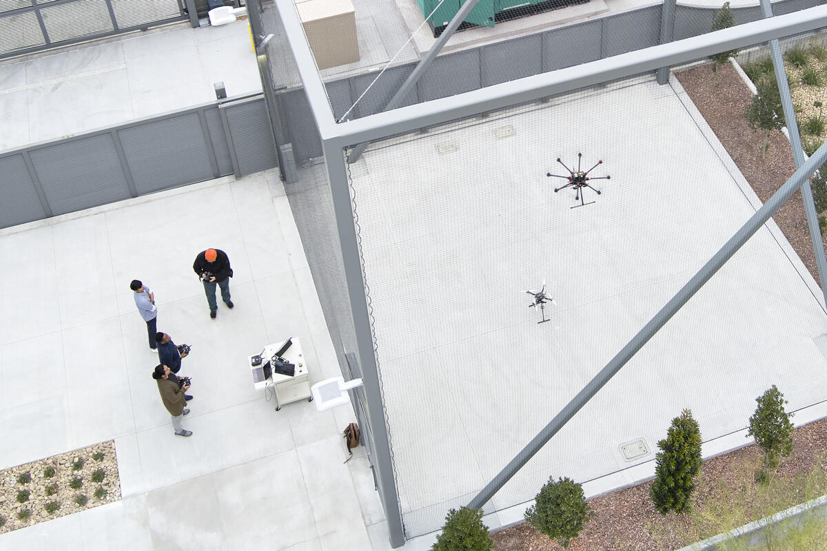 People flying drones inside a screened gate