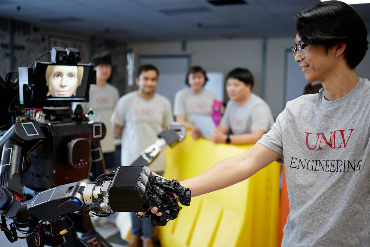 Students shaking hands with a robot