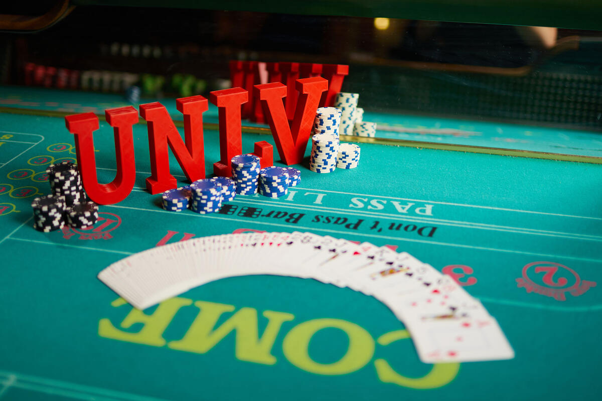 U-N-L-V letters on a poker table with a deck of cards laid out