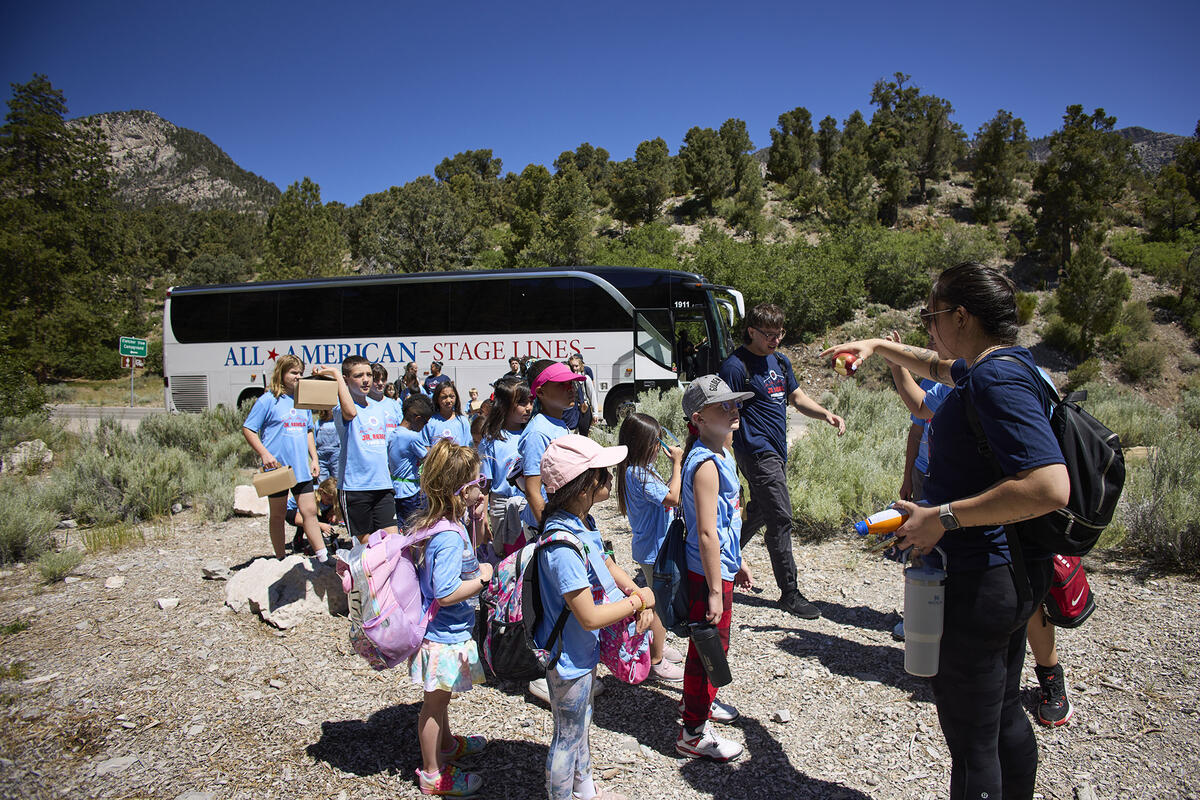 Picture of an adult talking to a group of children on a camping trip