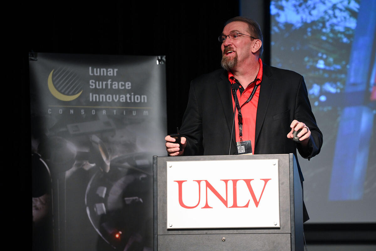 A man speaking in front of a podium 