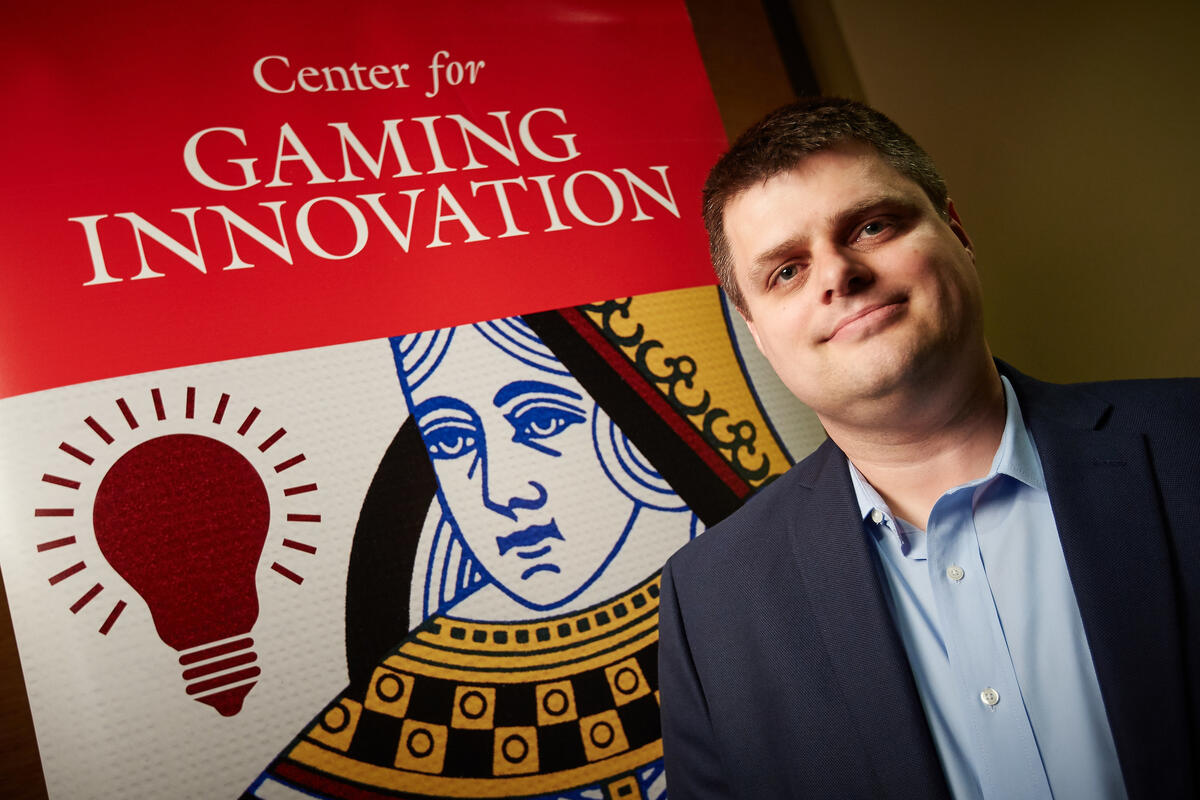 man posing in front of poster that looks like a playing card