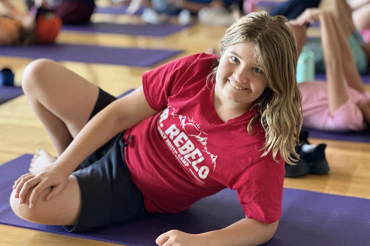 Child posed and smiling on yoga pad