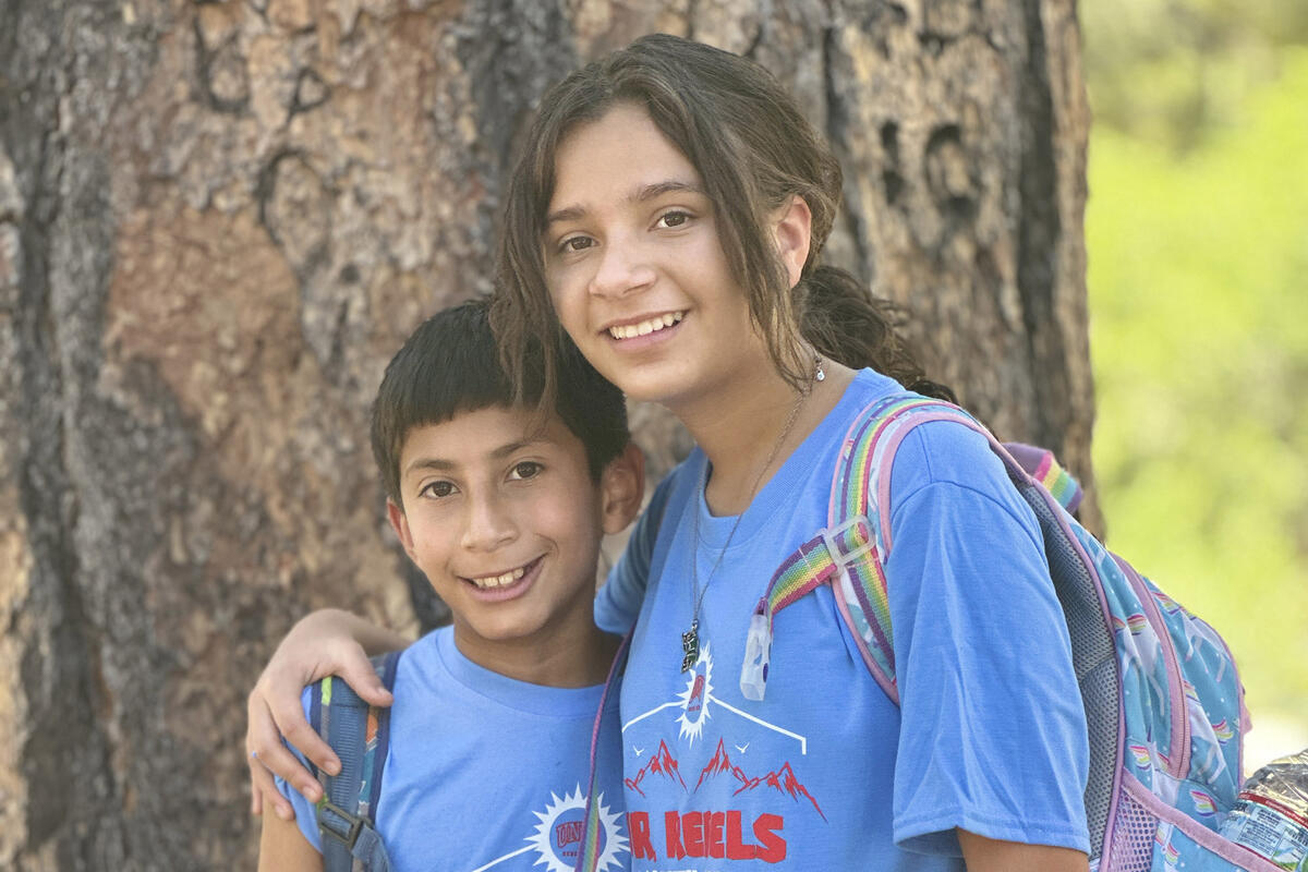 A girl and boy embracing while smiling at the camera