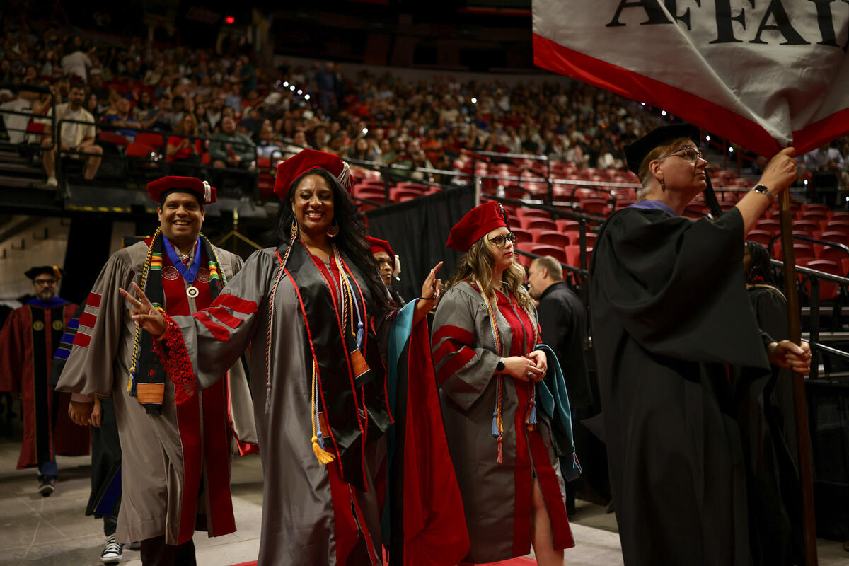 People in Ph.D. regalia walking into arena.
