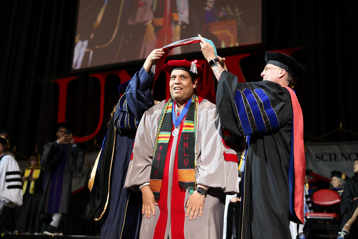 Ph.D student ceremoniously receives chords and stole