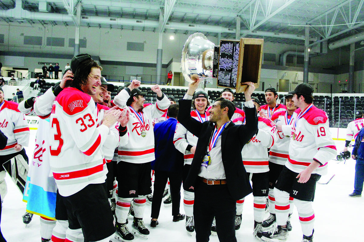 hockey team celebrating as coach holds trophy