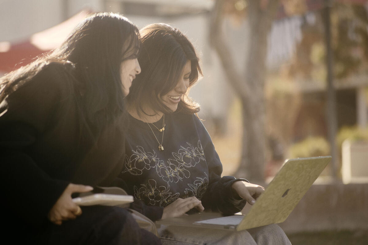 Two students outdoors looking at a computer screen