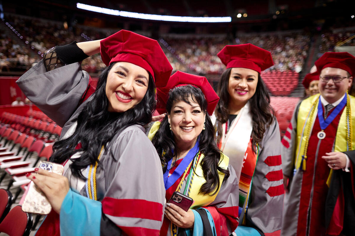  UNLV graduates celebrating in academic regalia during a commencement ceremony at the Thomas & Mack Center.