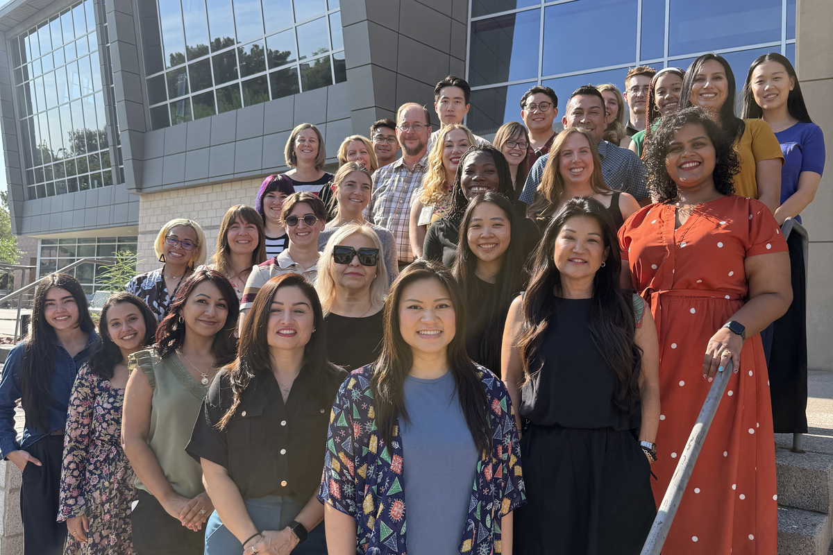 A group photo taken on the stairs outside of a glass building