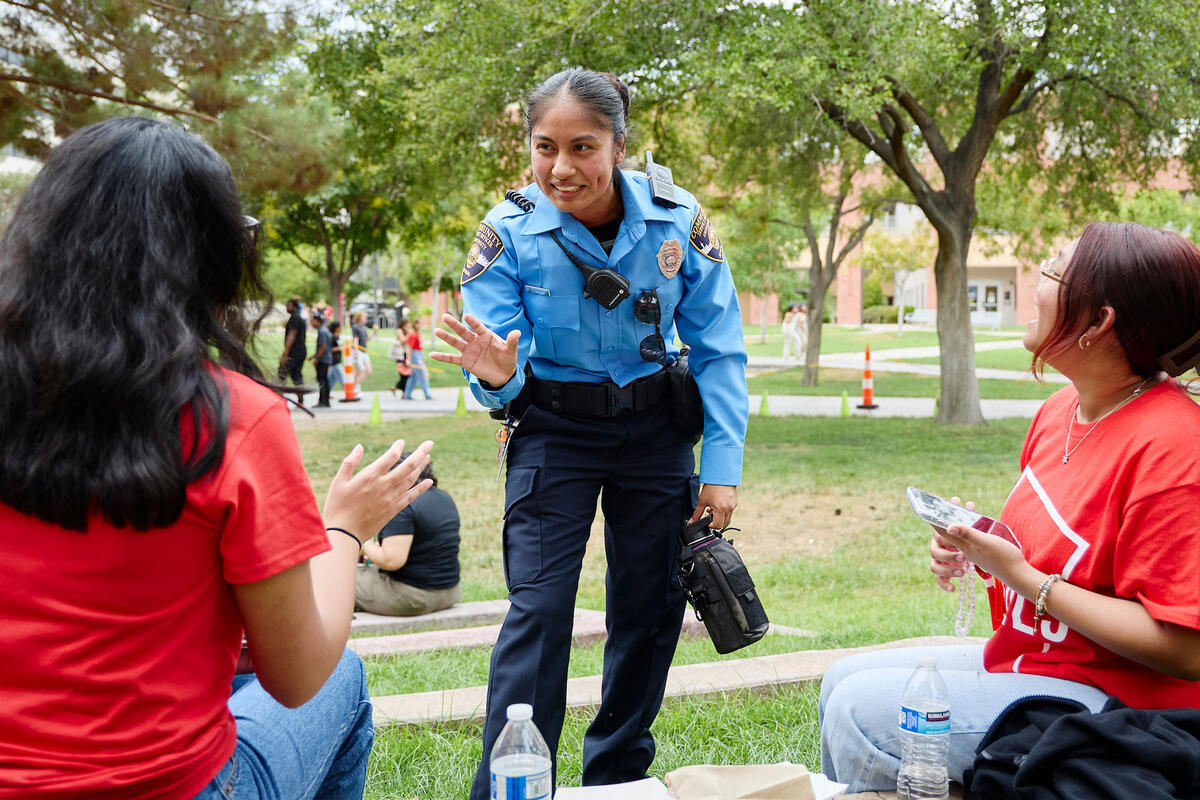officer in blue uniform talking with two women in red shirts