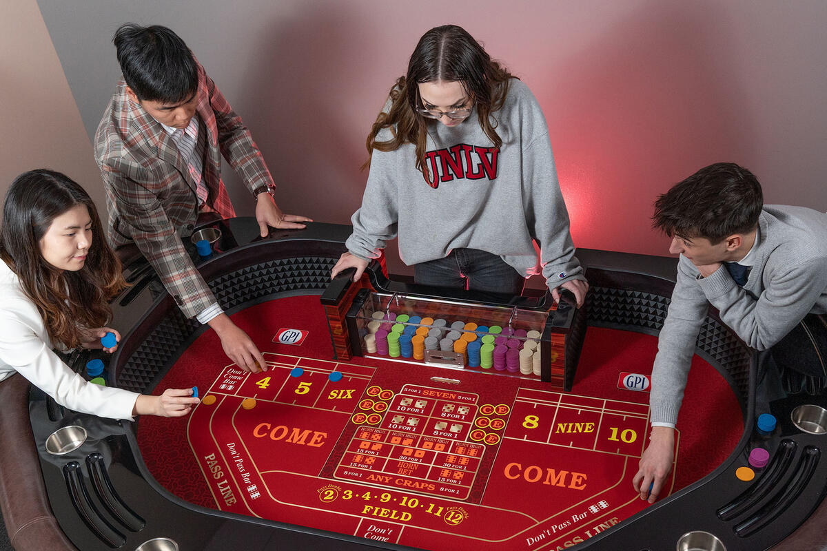 Four students leaning over a craps table